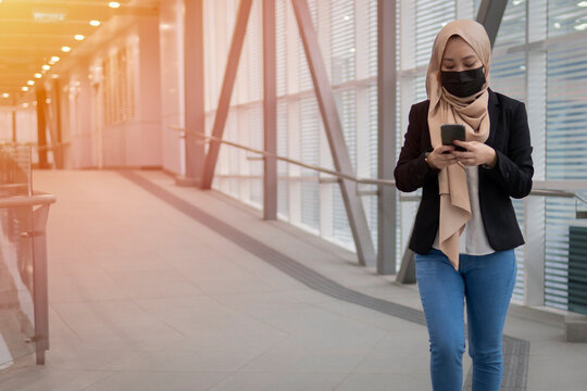 Young Malay Lady Wearing Face Mask Holding Smartphone