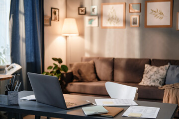 Image of desk with laptop on it for online work in the living room at home