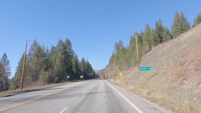 POV time lapse driving down winding mountain road in the fall by larch forest - British Columbia