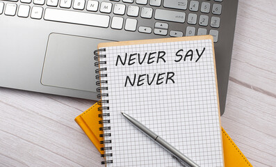 NEVER SAY NEVER text written on a notebook on the laptop