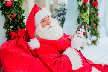 Santa claus using the phone outdoors. Merry Christmas.