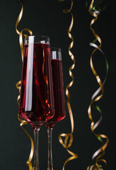 Red drink in high champagne glasses on a black background. Festive, Christmas, New Year's background card greeting