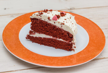 Slice of red velvet cake on a white wooden table