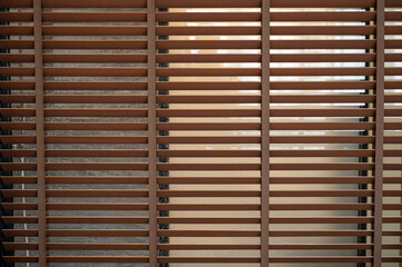 Pattern of brown wooden blinds on glass window