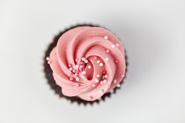 Pink cupcake with sugar pearls and raspberry cream from above