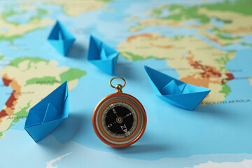 Bright paper boats and compass on world map