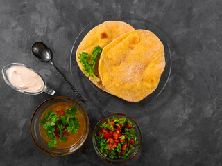Homemade corn flatbread cilantro greens tomato salsa. Handmade mexican Tortilla Taco Quesadilla vegetable. Traditional Indian Makki ki roti bread top view. Gluten free flour dough authentic cuisine.