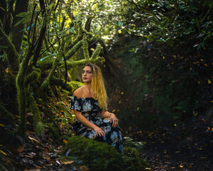 attractive blonde woman in a fantasy forest full of moss and green color