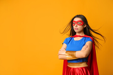 Confident young woman wearing superhero costume on orange background, space for text
