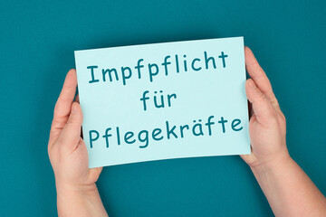 The word compulsory vaccination is standing on the paper, german language, mandatory vaccine, covid-19 regulations