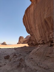 Dans la zone protégée du désert de Wadi Rum en Jordanie, avec de hautes montagnes rocheuses, exploration dans l'inconnu, sous un soleil et forte chaleur, parcourir du sable sans limite, dans l'ombre
