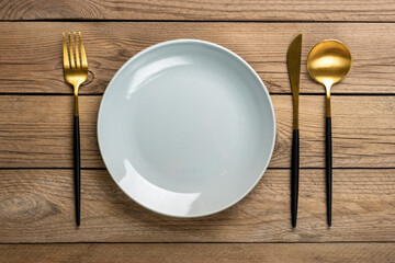 empty round gray plate, fork, knife, spoon on wooden table Top view Flat lay Dishes for breakfast,...