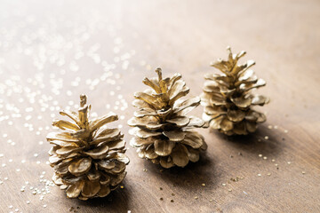 natural golden cones on a wooden table with gold spangles in the shape of stars, among fir branches 