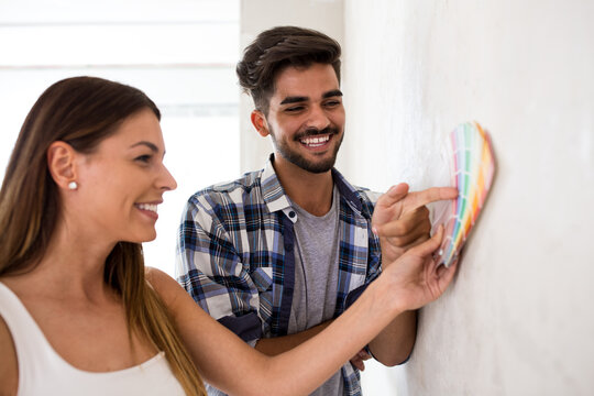 Young happy couple choosing colors for painting their home