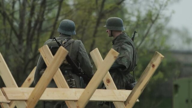 2 Wehrmacht soldiers sentries in German army uniform are talking to each other during reconstruction of invasion to USSR 22 June 1941 at World War 2 on Eastern front against Soviet Union.