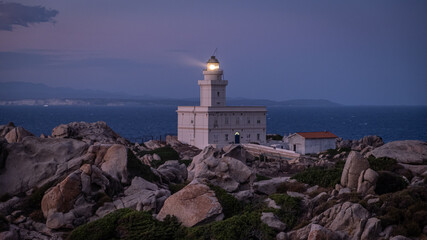 Fototapeta na wymiar Lighthouse in Capo Testa, Sardinia Italy after sunset. Lighthouse on a rocky shore next to the ocean during dusk. 