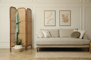 Stylish living room with folding screen and sofa. Interior design