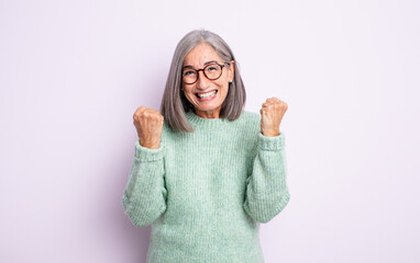 senior pretty woman shouting triumphantly, laughing and feeling happy and excited while celebrating...