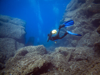 Fototapeta na wymiar Scuba diver from behind. Diving in clear water. Rocks underwater. Underwater diving. Sardinia diving