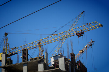 Fototapeta premium Tower cranes are working on the construction of a multi-storey building
