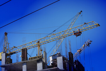 Fototapeta premium Tower cranes are working on the construction of a multi-storey building