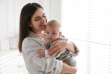 Young woman with her little baby near window at home