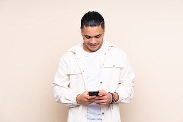 Asian handsome man over isolated background sending a message with the mobile