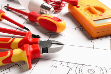 Set of electrician's tools and accessories on paper sheets, closeup