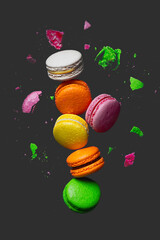 Different types of macaroons in motion falling on black background. Sweet and colorful french macaroons falling or flying in motion
