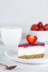 A piece of raw mousse cauliflower cake with strawberries on a light background. Sugar, gluten, lactose free, vegan.
