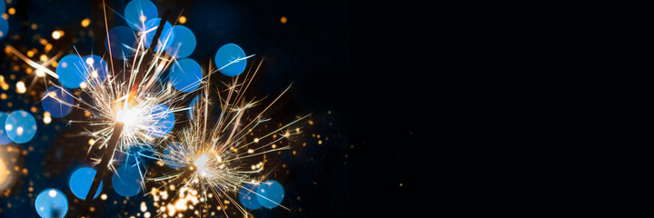 two classic sparklers with blue blurred bokeh lights