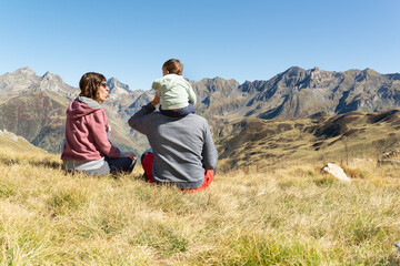 Fototapeta premium Playful couple and baby having a rest during a trekking day at the mountains. Happy family having fun at the mountains. 