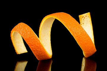 Spiral orange peel on a black background. Citrus twist.