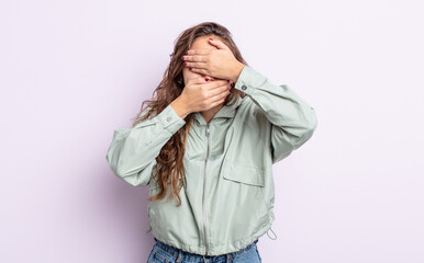 hispanic pretty woman covering face with both hands saying no to the camera! refusing pictures or...