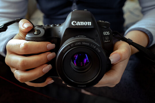 Canon 6D Mark II camera in female hands. A woman photographer is holding a Canon camera in her hands