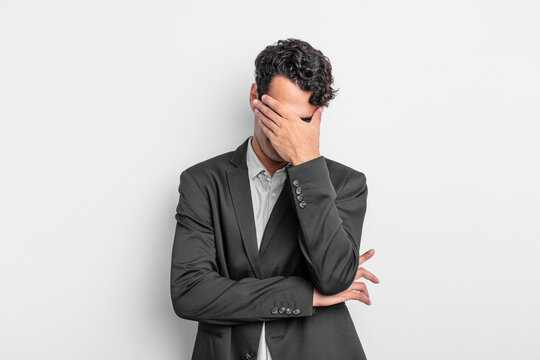 young businessman looking stressed, ashamed or upset, with a headache, covering face with hand
