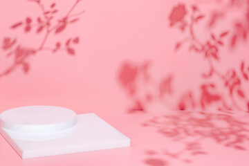 Abstract minimal nature scene - empty stage and white podium on pink background and soft shadows of rose flowers and leaves. Pedestal for cosmetic product and packaging mockups display presentation