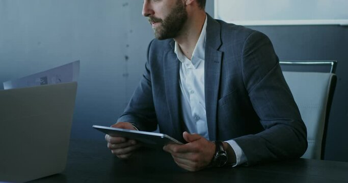 A young man with a tablet in his hands, talks with his boss in his office