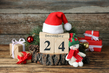 December 24 - Christmas Eve. Wooden block calendar and festive decor on table - obrazy, fototapety, plakaty