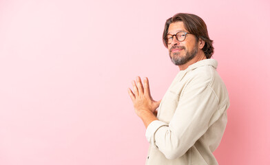 Senior dutch man isolated on pink background scheming something