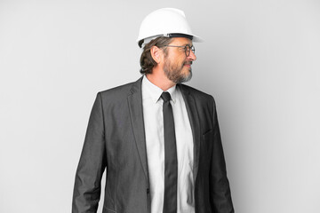Young architect man with helmet over isolated background looking side