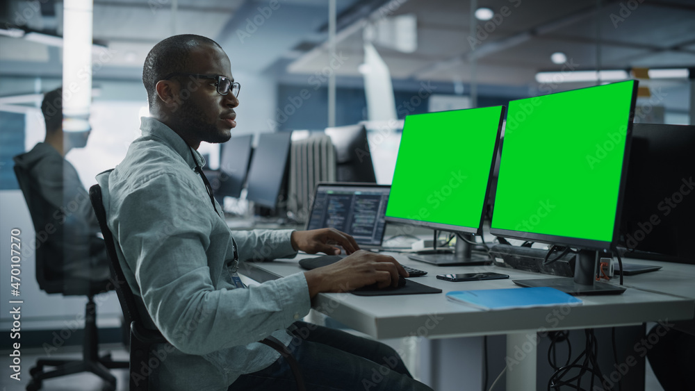 Leinwandbilder Multi-Ethnic Office: Black IT Programmer Working on Computer with Green Screen Chroma Key Display. Male Software Engineer Developing App, Program, Video Game. Terminal with Code Language.