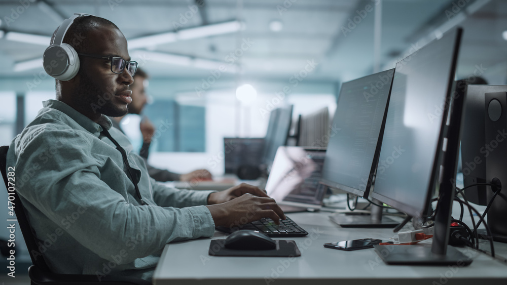 Aufkleber office: energetic black it programmer puts on headphones starts working on desktop computer. male we