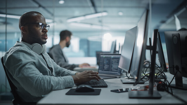 Authentic Office: Enthusiastic Black IT Programmer Starts Working on Desktop Computer. Male Website Developer, Software Engineer Developing App, Video Game. Terminal with Coding Programming Language - Powered by Adobe