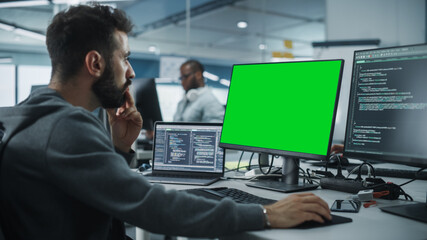 Multi-Ethnic Office: White IT Programmer Working on Computer with Green Screen Chroma Key Display....