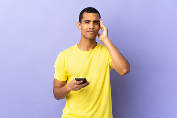 African American man over isolated purple background using mobile phone unhappy and frustrated with...
