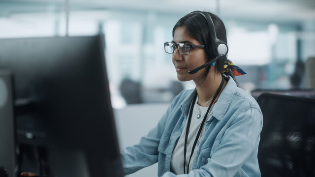 Call Center Office: Portrait of Friendy Indian Female IT Customer Support Specialist Working on Computer. Business Entrepreneur Using Headset to Talk with Client via Online Video Conference Call