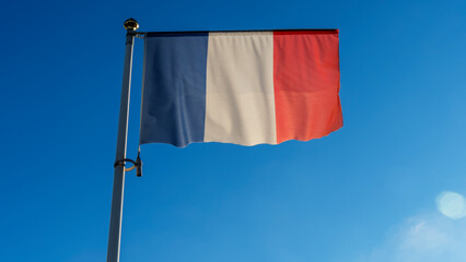 French flag with blue sky and sun with lens flare. Diplomacy concept. International relations.