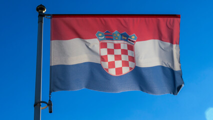 National flag of Croatia on a flagpole in front of blue sky with sun rays and lens flare. Diplomacy concept.