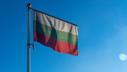 National flag of Bulgaria on a flagpole in front of blue sky with sun rays and lens flare. Diplomacy concept.